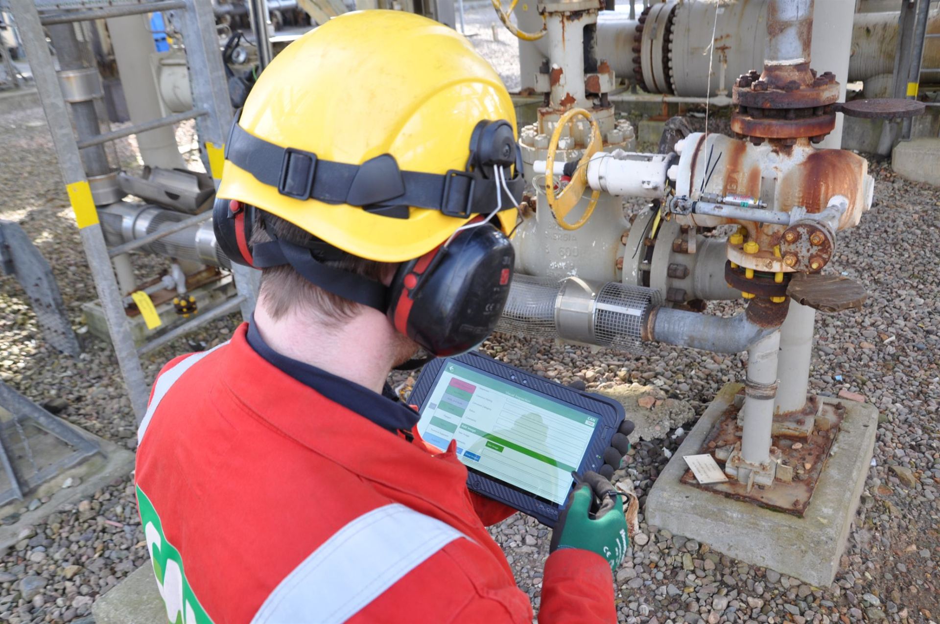 Inspector recording a visual inspection on CANtab beside process pipework